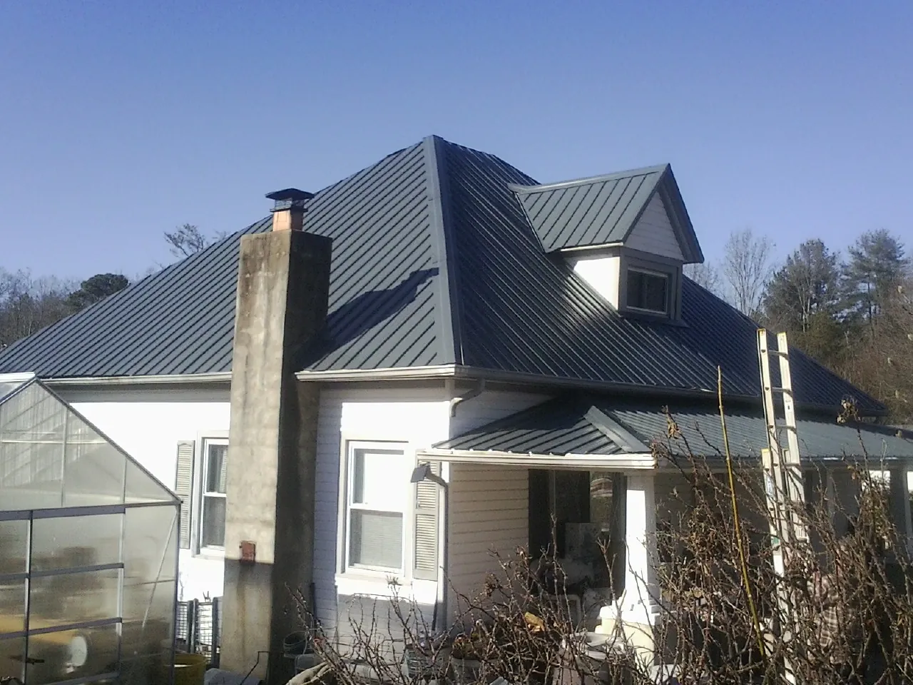 Dark blue standing seam metal roof on a white farmhouse with dormer — Slate & Tile Roof Repair by Roofing Brothers in Norwell