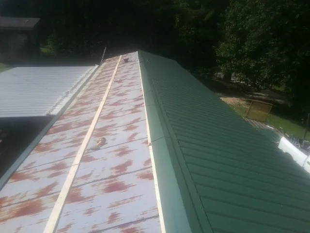 Old rusted panels beside newly installed green metal roofing — Wind Damage Roof Repair by Roofing Brothers in Norwell