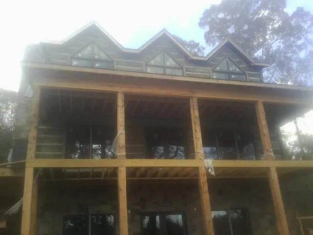 Dormers and porch framing on a large log home under construction — Roof Coating work by our crew in Norwell