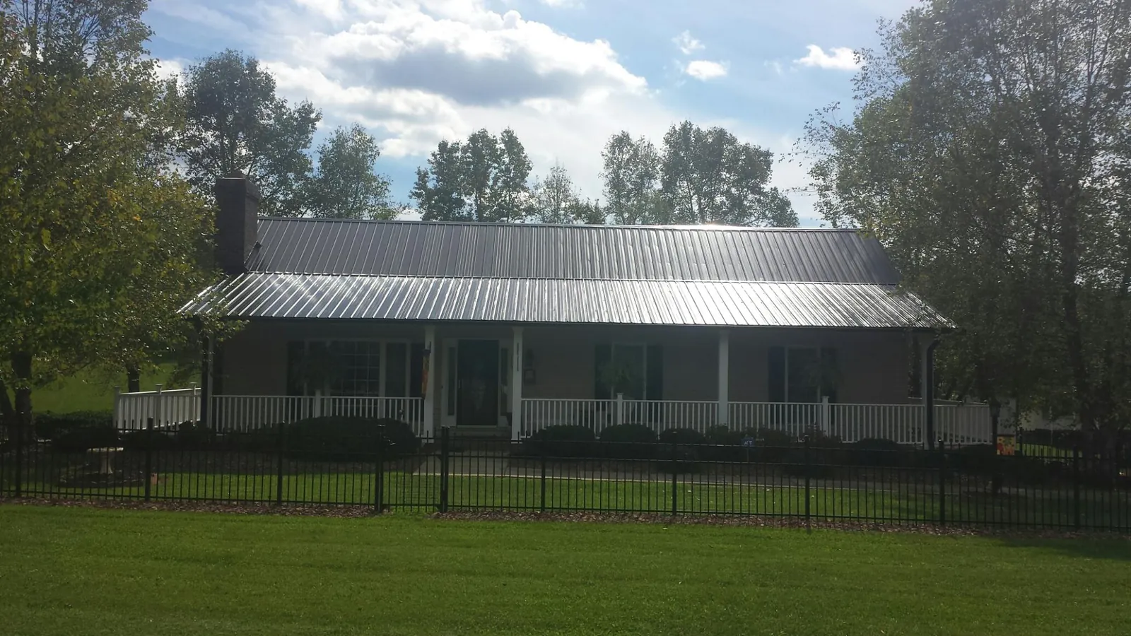 Gray metal roof on a brick ranch with a full width front porch — Gutter Guard Installation work by our crew in Norwell