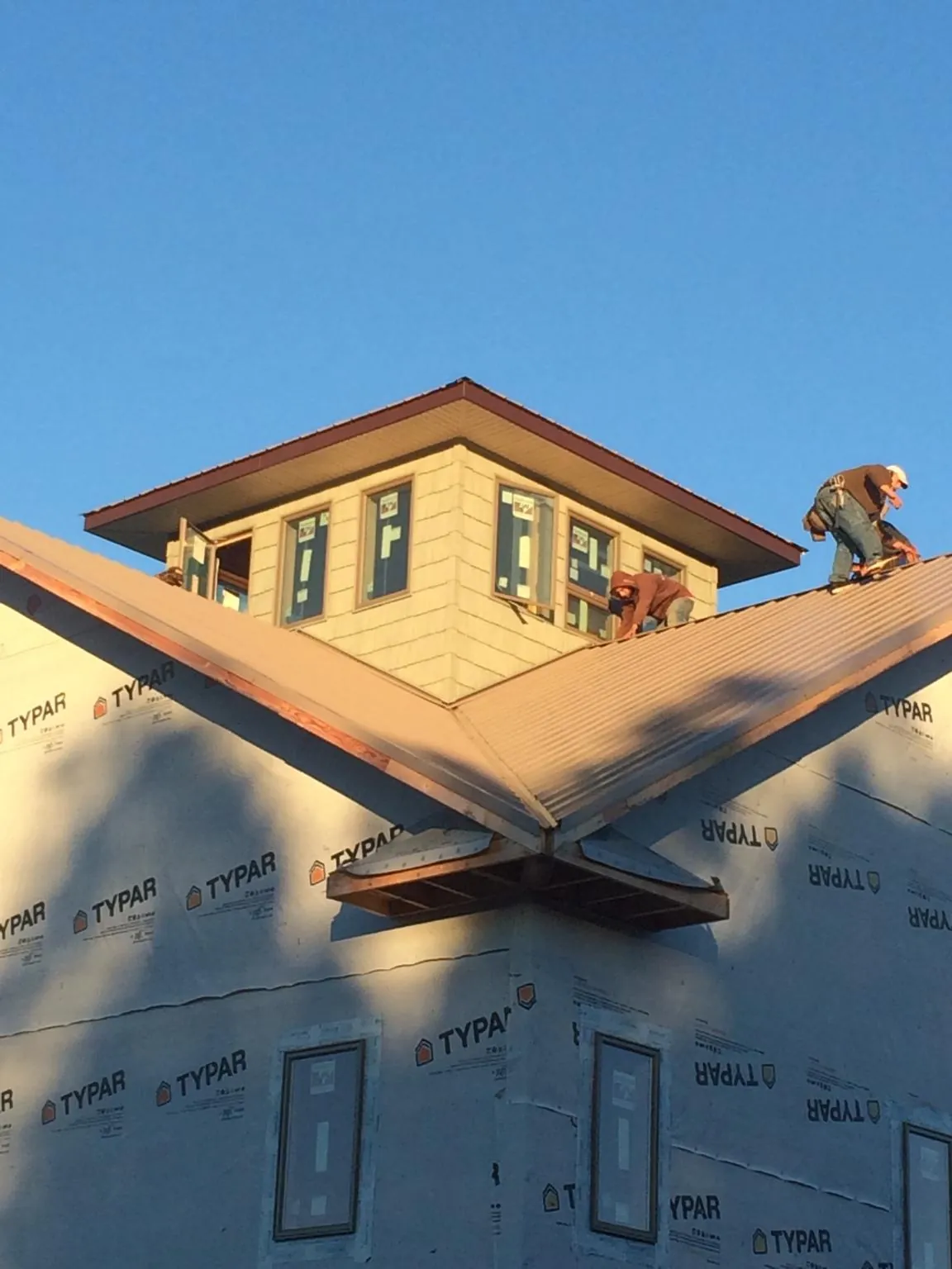 Roofers working around a rooftop cupola on a new metal roof at sunset — Roof Waterproofing in Norwell by Roofing Brothers